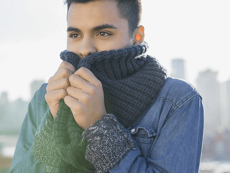 man wrapping scarf around his neck and mouth