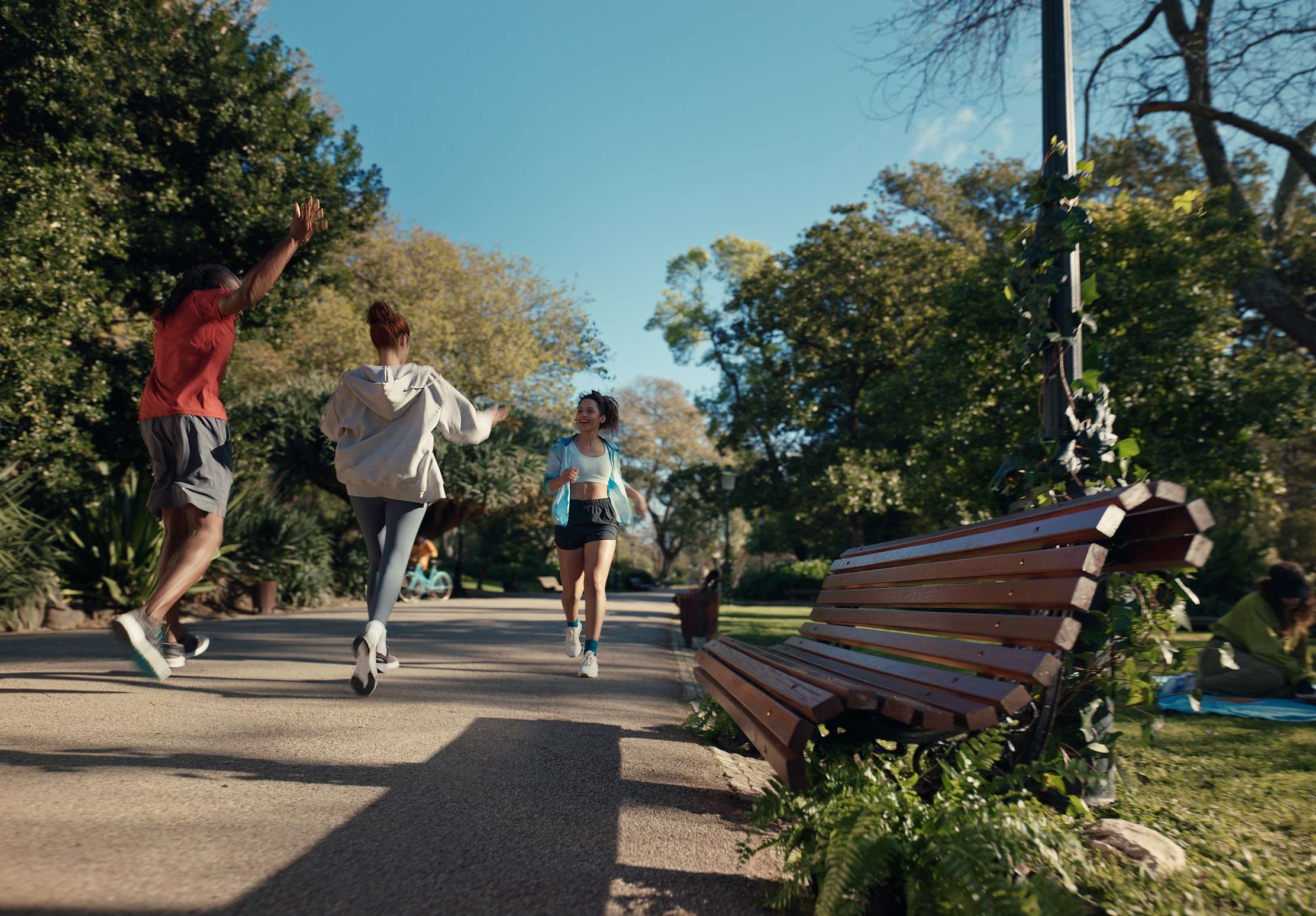 running joggers greet each other next to park bench